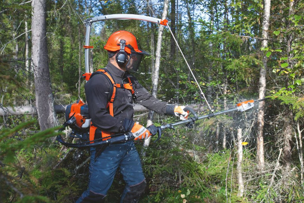 Man som röjer med kedjeröjsåg i skogen